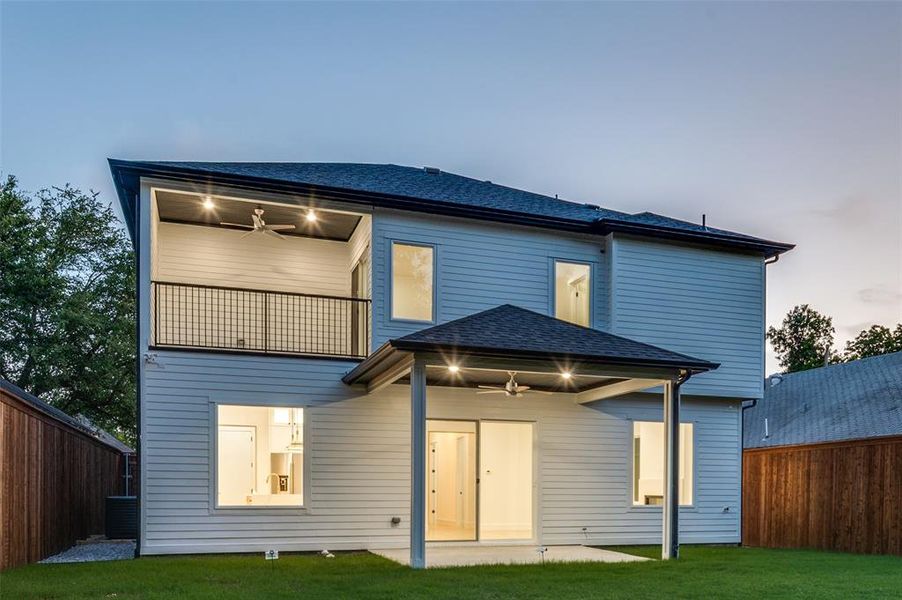 Back of house at dusk featuring roof with shingles and a ceiling fan Back of house at dusk featuring roof with shingles and a ceiling fan