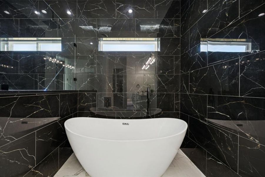 Full bath with tile walls, marble tiled flooring, and a soaking tub