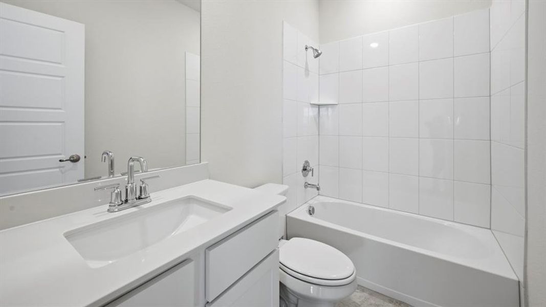 Bathroom featuring a vanity with an integrated sink, polished chrome faucet, and expansive wall-mounted mirror Bathroom featuring a vanity with an integrated sink, polished chrome faucet, and expansive wall-mounted mirror