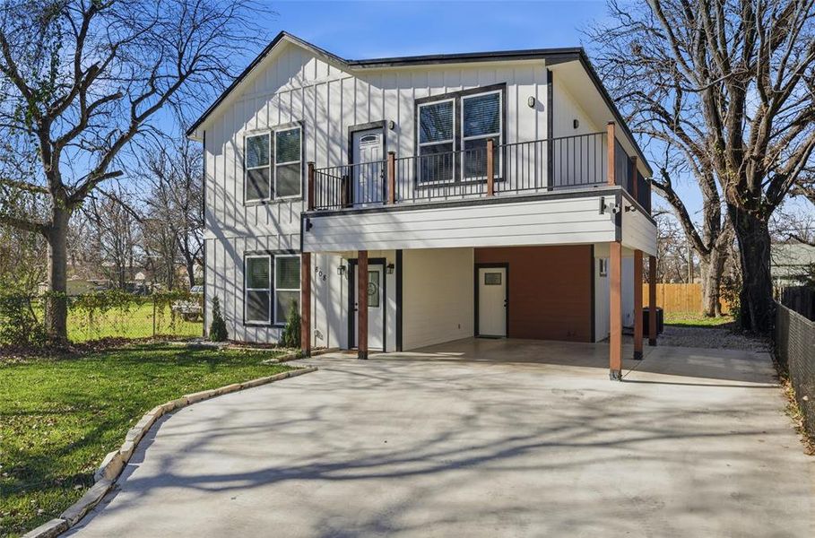 View of front of home with driveway, board and batten siding, a carport, and a balcony View of front of home with driveway, board and batten siding, a carport, and a balcony
