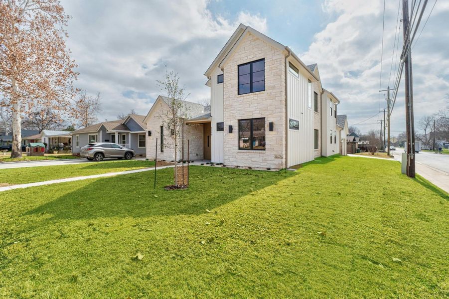View of front facade with stone siding, a front lawn, and a residential view