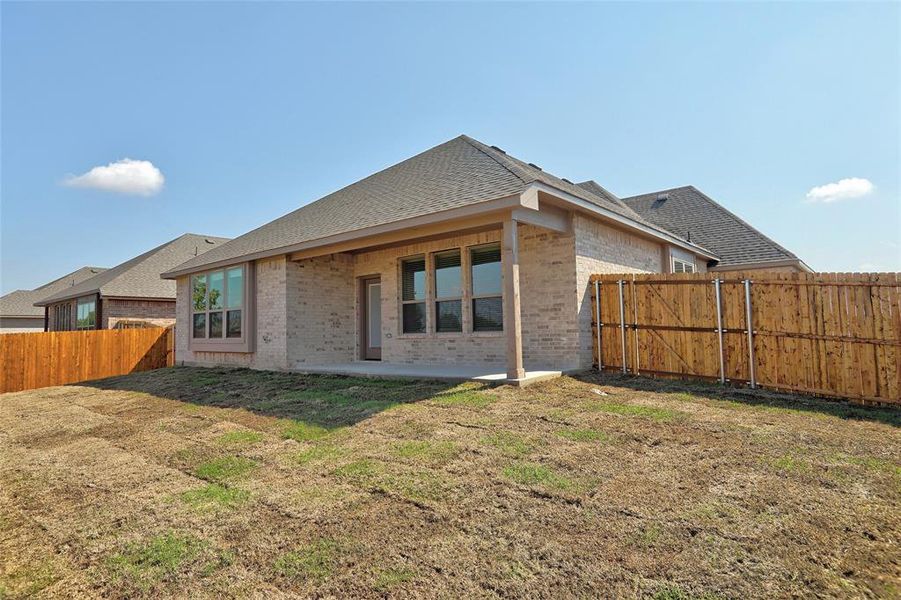 Rear view of house with a fenced backyard, brick siding, a patio, and roof with shingles Rear view of house with a fenced backyard, brick siding, a patio, and roof with shingles