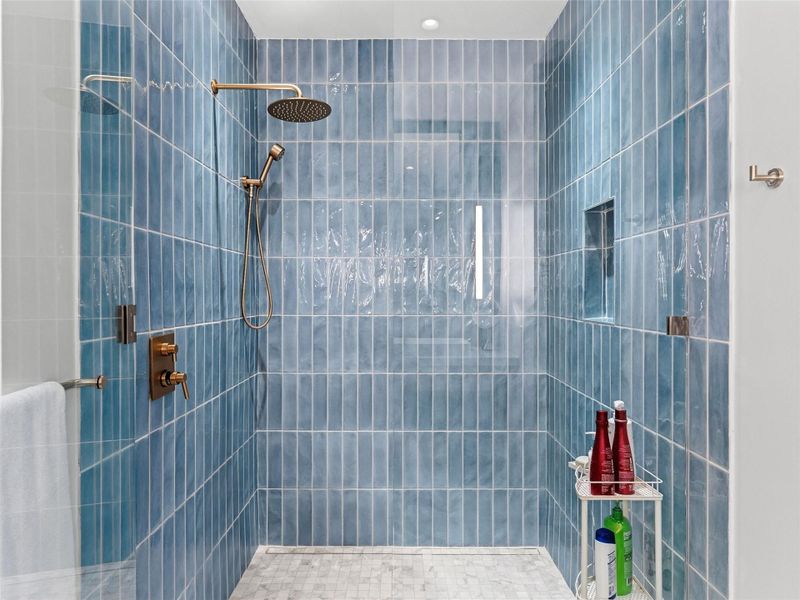 Tiled shower featuring blue vertical subway tiles and a contrasting mosaic tile floor and is wheelchair accessible Tiled shower featuring blue vertical subway tiles and a contrasting mosaic tile floor and is wheelchair accessible