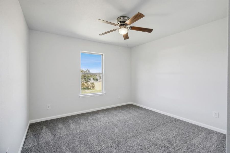 Carpeted spare room featuring ceiling fan