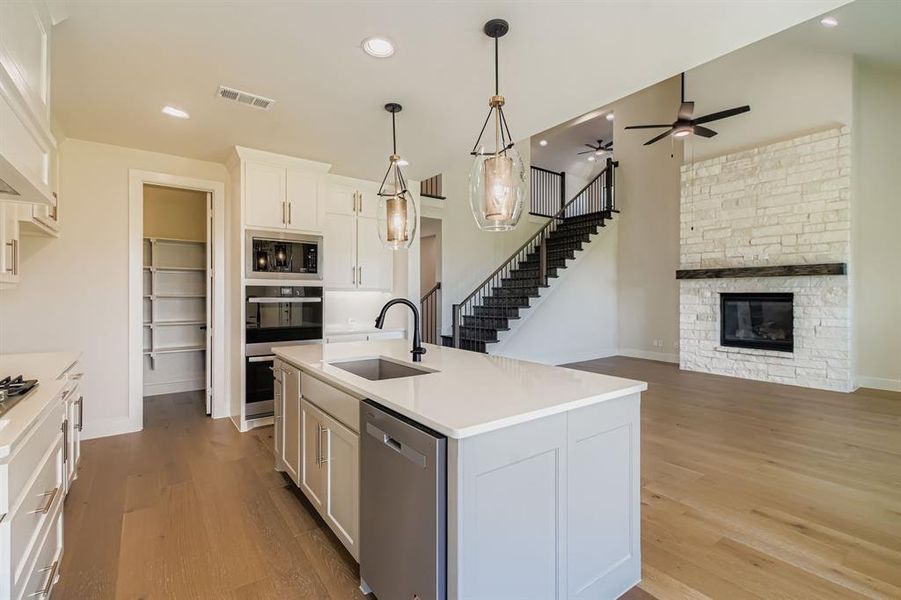 Kitchen featuring stainless steel appliances, wood finished floors, white cabinetry, ceiling fan, and light countertops