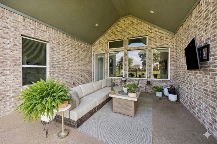 Vaulted covered patio extends the living space outdoors, complete with recessed lighting and a mounted TV setup for easy entertaining. Framed by brick and a wall of windows, the space overlooks the backyard with peaceful water and greenbelt views. Vaulted covered patio extends the living space outdoors, complete with recessed lighting and a mounted TV setup for easy entertaining. Framed by brick and a wall of windows, the space overlooks the backyard with peaceful water and greenbelt views.