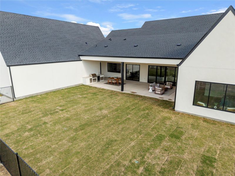 Rear view of house featuring stucco siding, a patio, a shingled roof, and outdoor seating