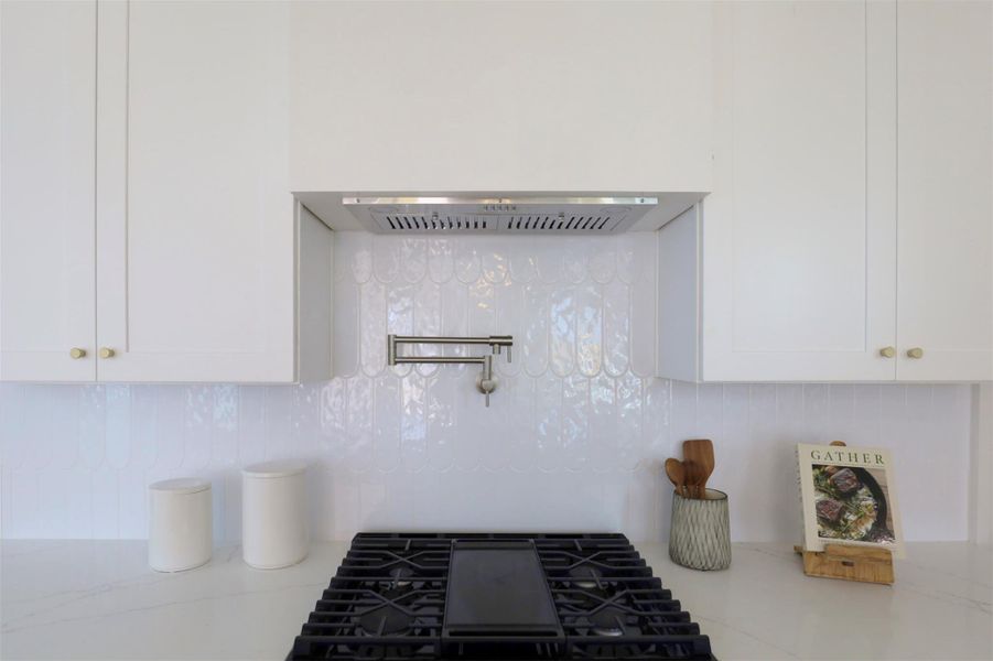 Gas range is complemented by the  pot filler and subtle yet striking backsplash.