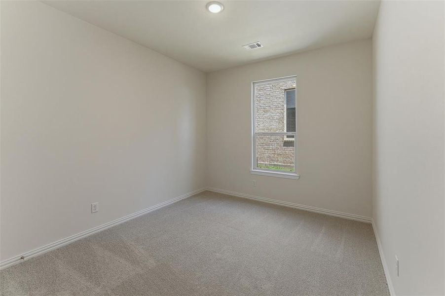 Carpeted interior room featuring a window with exterior stone cladding visible, recessed ceiling light, and baseboard trim