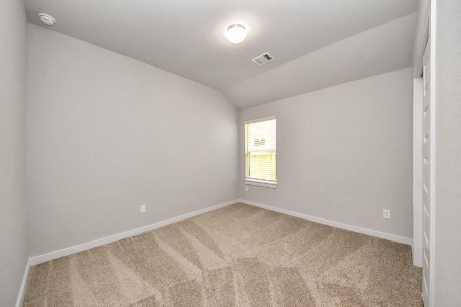 Secondary bedroom features plush carpeting, large windows that let in plenty of natural light, bright paint, and spacious closets. Sample photo of completed home with similar floor plan. Actual colors and selections may vary.