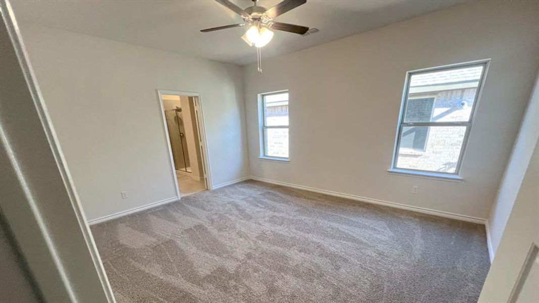 Unfurnished bedroom featuring light carpet, ceiling fan, and ensuite bath