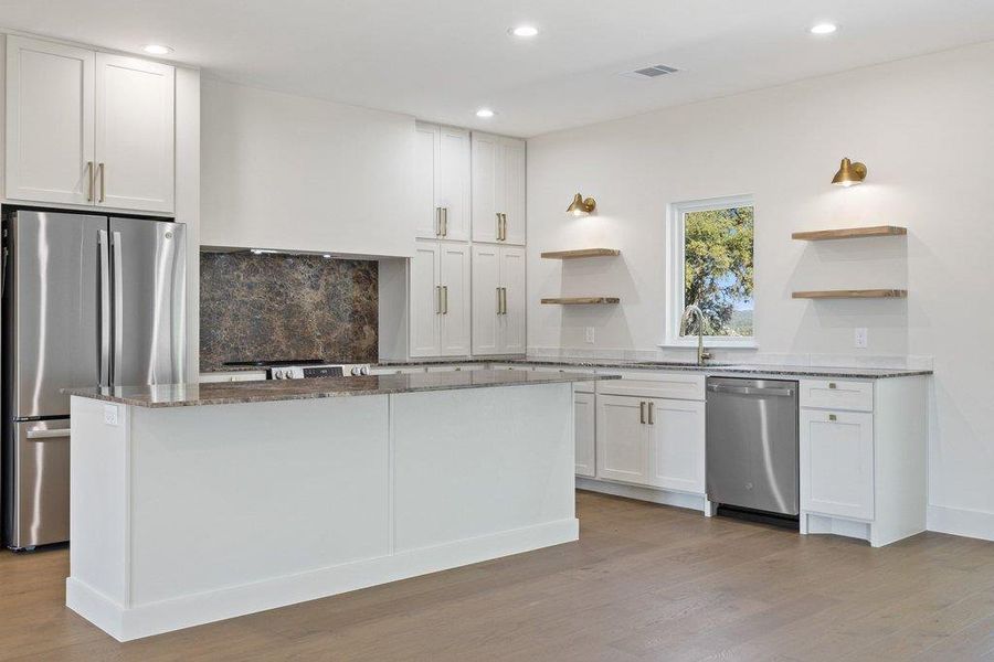 Kitchen with open shelves, dark stone counters, white cabinets, stainless steel appliances, and light wood-style floors