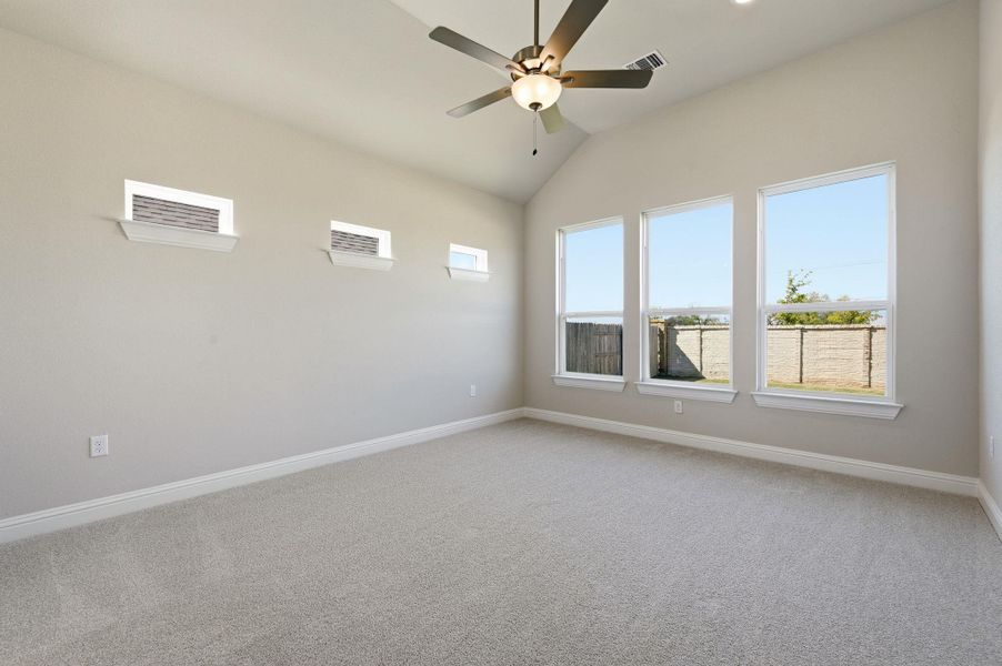 Empty room featuring light carpet, lofted ceiling, and a ceiling fan Empty room featuring light carpet, lofted ceiling, and a ceiling fan