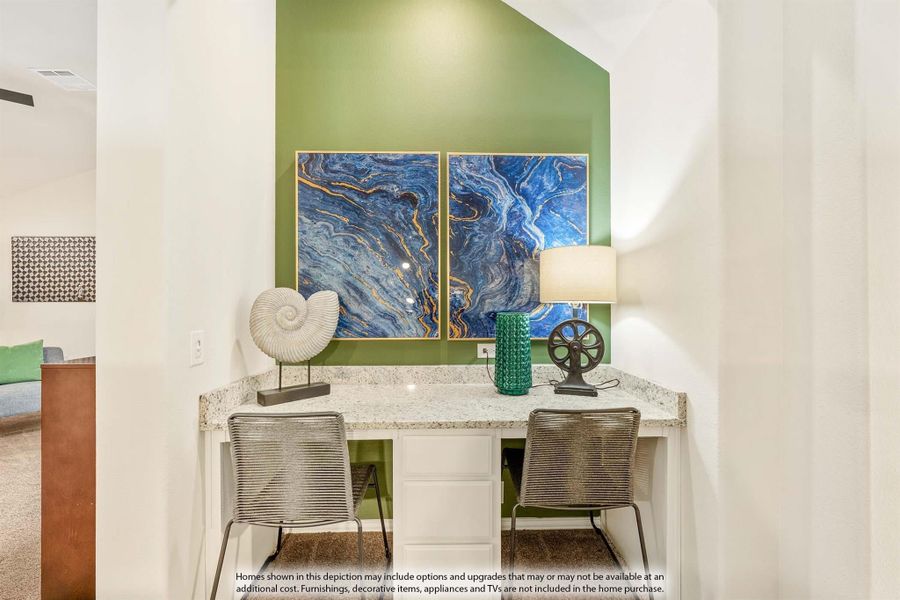 Built-in desk nook with granite countertop, two chairs, and green accent wall with blue artwork above
