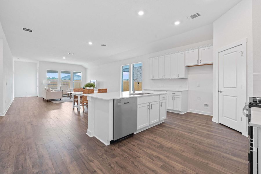 Kitchen with white cabinets, recessed lighting, dark wood-style flooring, appliances with stainless steel finishes, and a kitchen island with sink Kitchen with white cabinets, recessed lighting, dark wood-style flooring, appliances with stainless steel finishes, and a kitchen island with sink