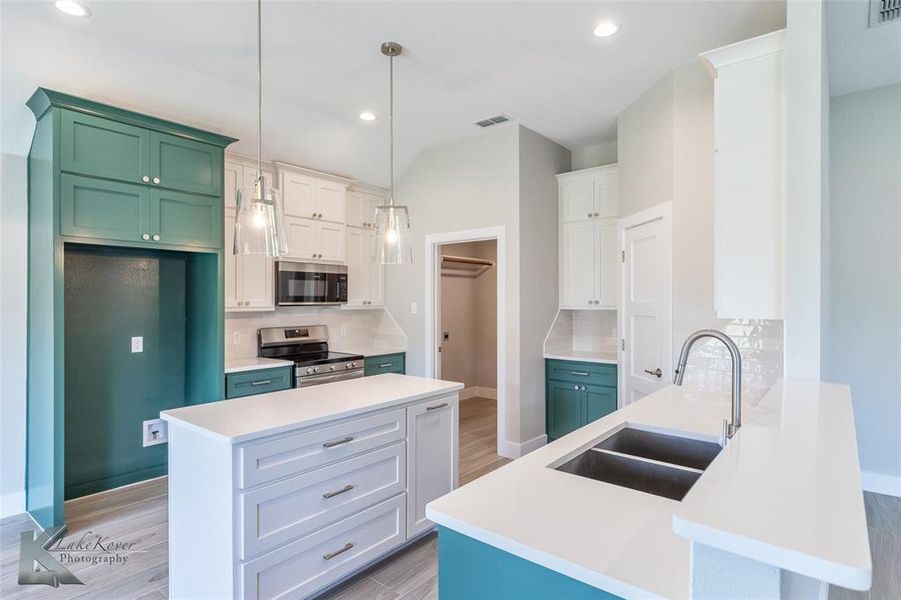 Kitchen featuring light wood-style flooring, decorative backsplash, stainless steel appliances, a peninsula, and recessed lighting