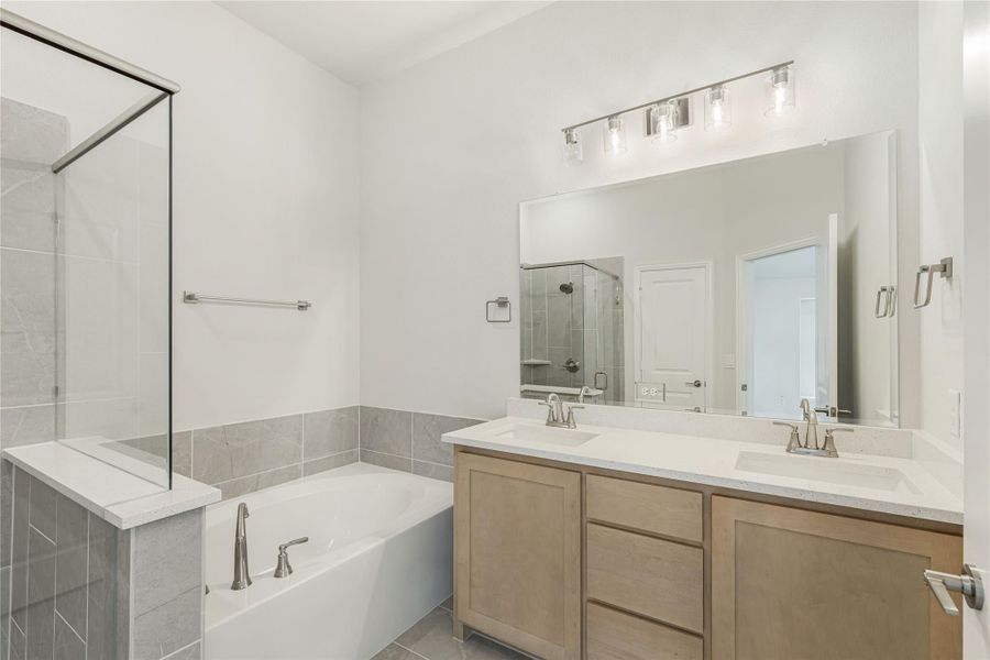 Bathroom with double sink vanity, soaking tub, glass shower, and gray tile floors Bathroom with double sink vanity, soaking tub, glass shower, and gray tile floors