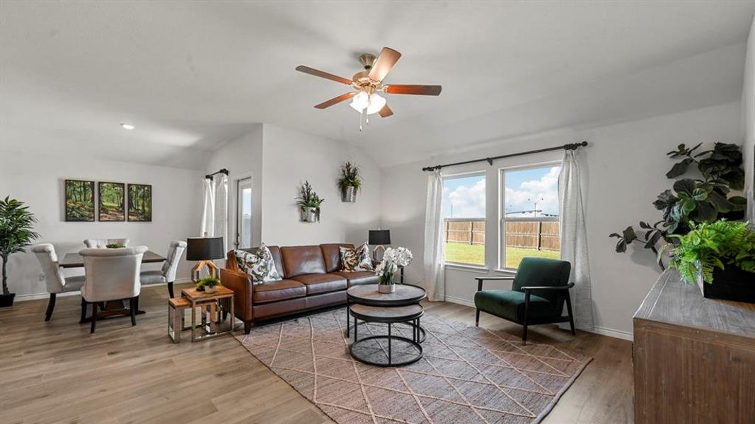 Living room featuring light wood-type flooring, lofted ceiling, and ceiling fan