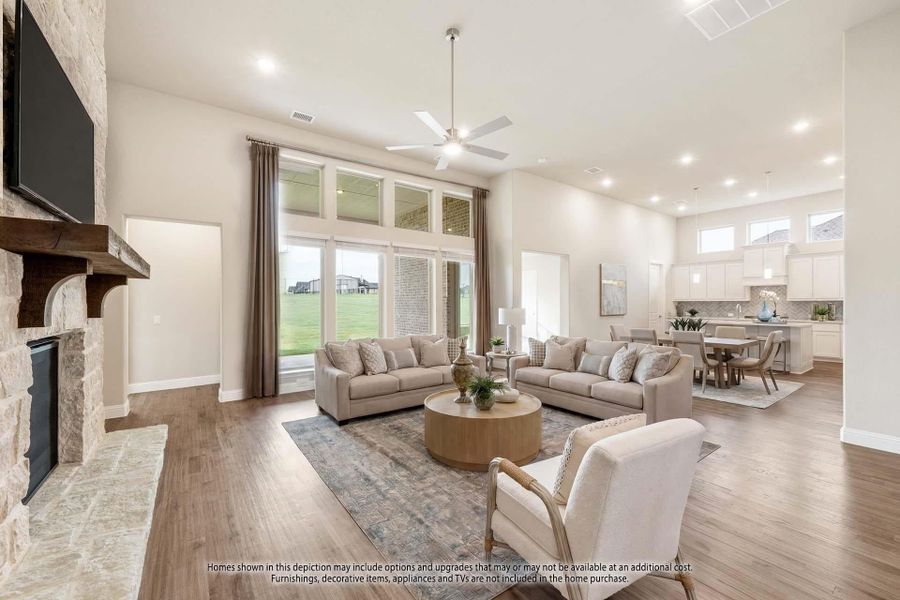 Open-concept living room with stone fireplace, high ceilings, hardwood floors, and view into kitchen and dining area. Open-concept living room with stone fireplace, high ceilings, hardwood floors, and view into kitchen and dining area.