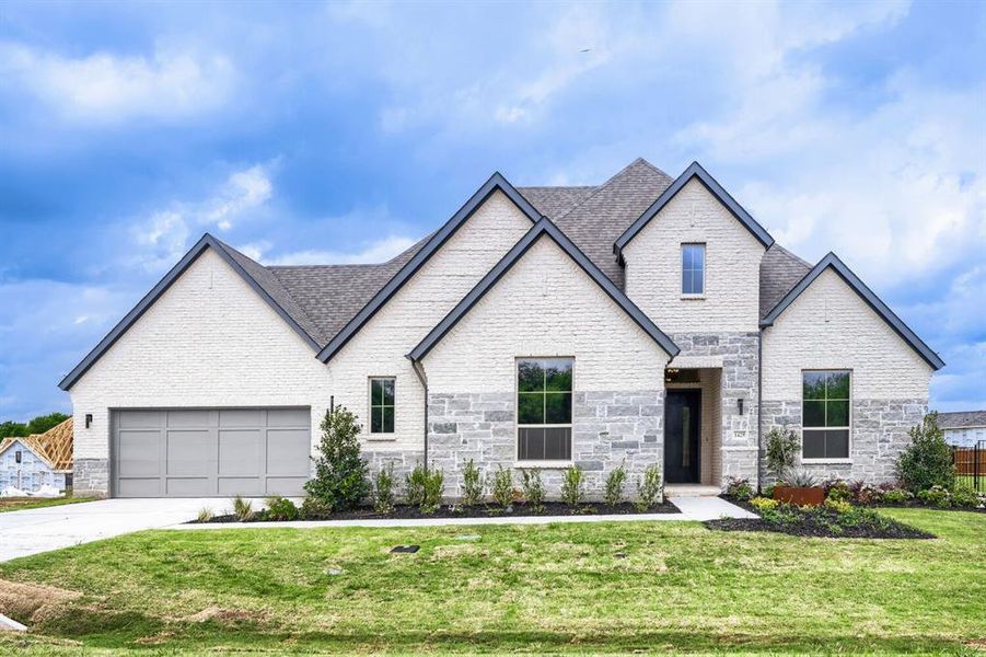 French country style house with stone siding, a front lawn, driveway, a garage, and a shingled roof