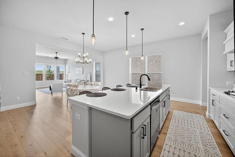 Contemporary kitchen island with a light-toned countertop, integrated stainless steel sink, and matte black faucet