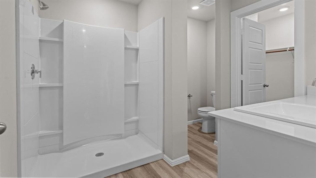 Full bathroom with wood finished floors, a stall shower, toilet, vanity, and recessed lighting Full bathroom with wood finished floors, a stall shower, toilet, vanity, and recessed lighting