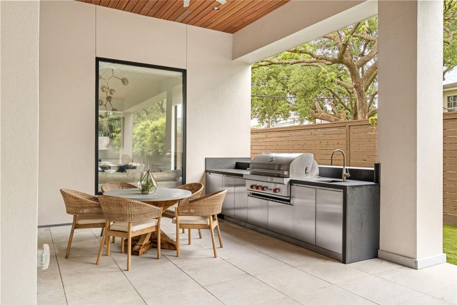 A fully equipped outdoor kitchen with built-in Wolf grill, SubZero beverage fridge, and covered dining space designed for effortless entertaining