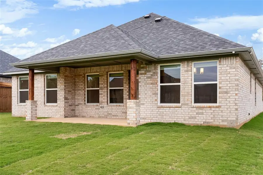 Rear view of property with a yard, roof with shingles, brick siding, and a patio