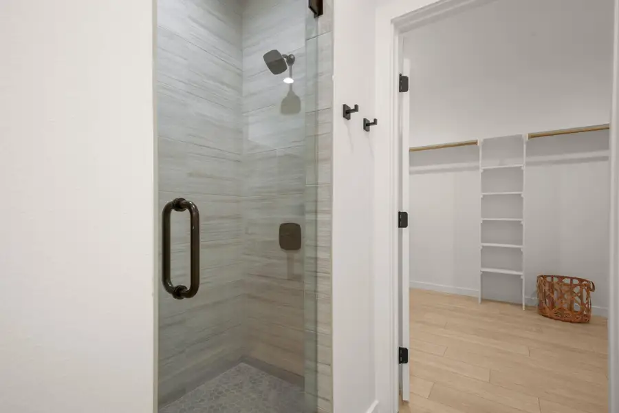 Full bath with a stall shower, a spacious closet, and light wood-style floors