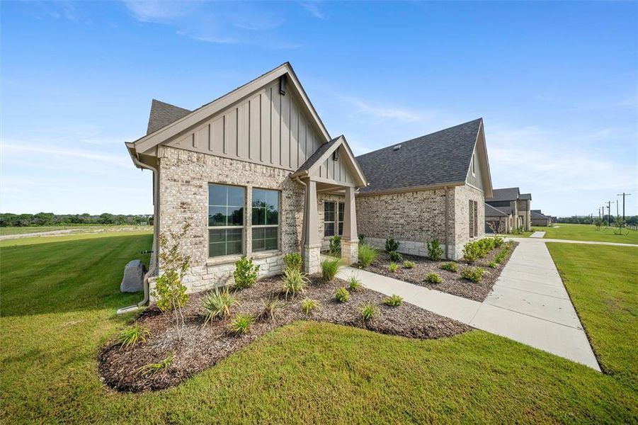 View of front facade featuring board and batten siding, a front lawn, brick siding, and a shingled roof View of front facade featuring board and batten siding, a front lawn, brick siding, and a shingled roof