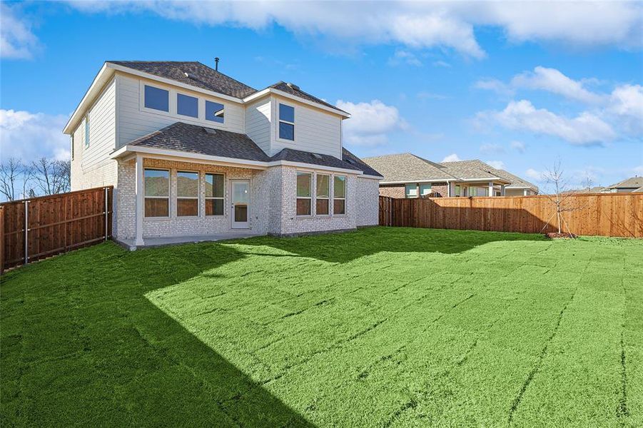 Rear view of house featuring a fenced backyard, brick siding, a patio area, and a shingled roof