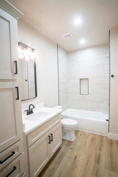 Full bathroom featuring visible vents, toilet, shower / tub combination, wood finished floors, and vanity