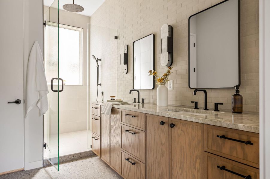 An elegant washroom showcases dual sinks, stone countertops, and a modern walk-in shower. An elegant washroom showcases dual sinks, stone countertops, and a modern walk-in shower.