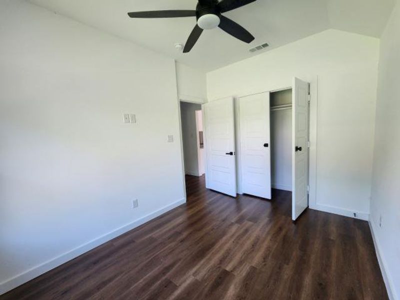 Unfurnished bedroom with dark wood-type flooring, ceiling fan, a closet, and vaulted ceiling Unfurnished bedroom with dark wood-type flooring, ceiling fan, a closet, and vaulted ceiling