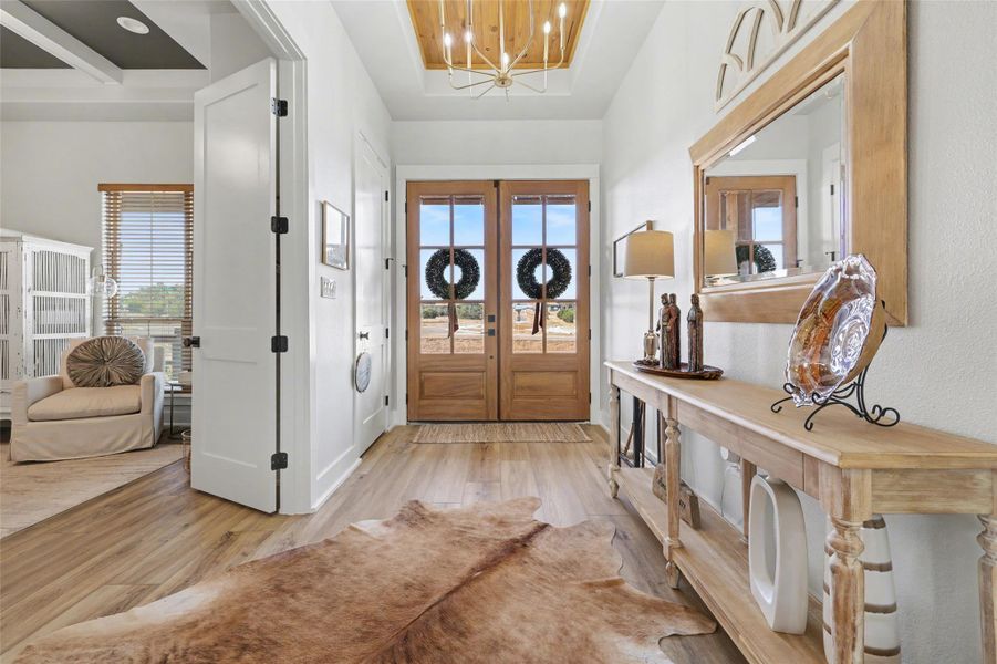 Entrance foyer with a chandelier, LVP floors, a raised wood ceiling feature and plenty of natural light