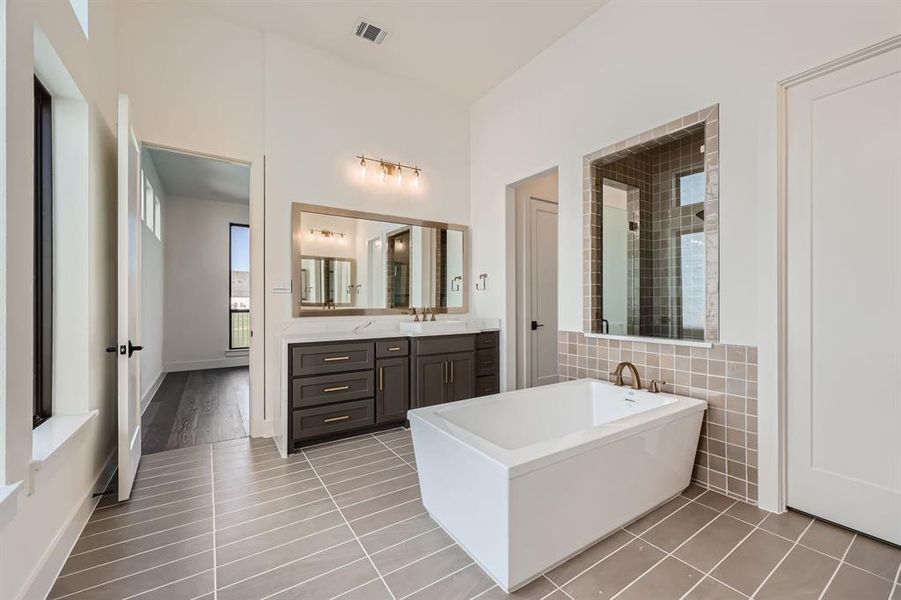 Bathroom featuring tile patterned flooring, shower with separate bathtub, and vanity