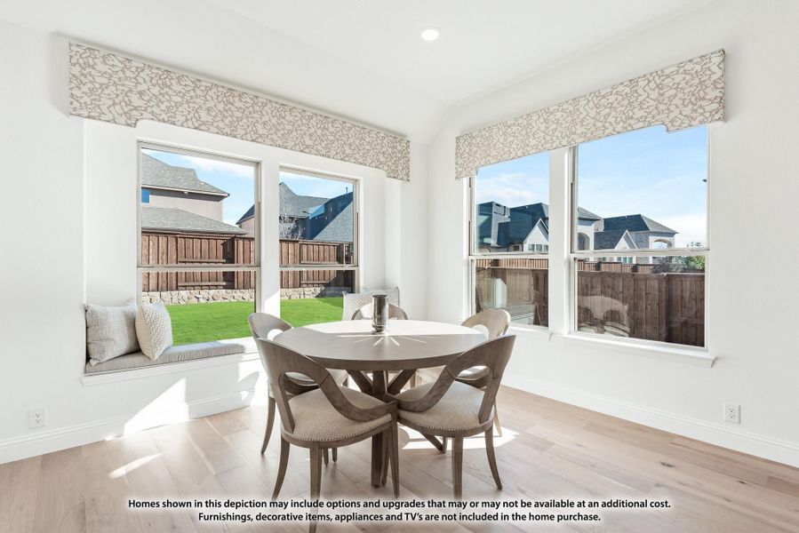 Bright breakfast nook with round dining table, window seat, and large windows overlooking backyard Bright breakfast nook with round dining table, window seat, and large windows overlooking backyard