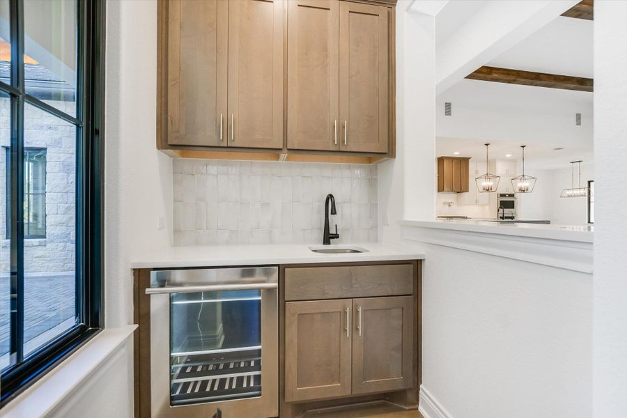 Bar with beverage cooler, decorative backsplash, plenty of natural light, beamed ceiling, and decorative light fixtures