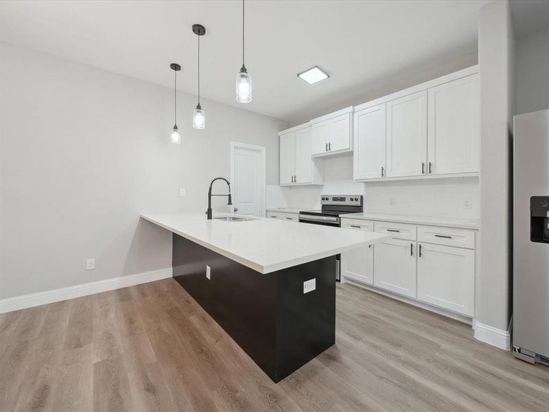 Kitchen featuring sink, white cabinets, decorative light fixtures, and white refrigerator with ice dispenser