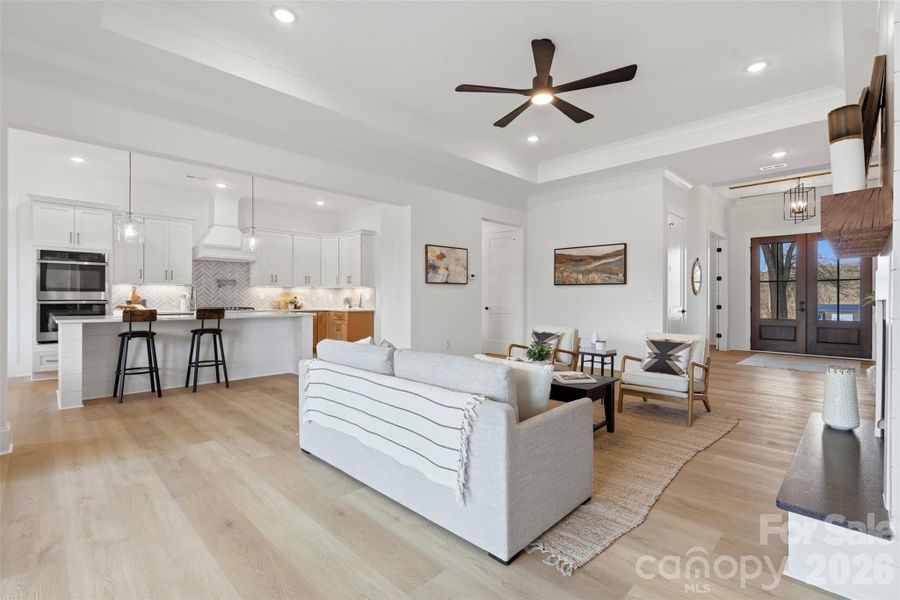 living room w/ ventless gas fireplace, tray ceiling, and 8ft sliding glass doors to the covered rear patio