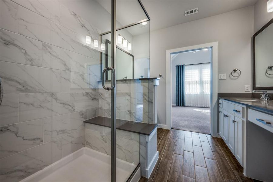 Bathroom featuring vanity, baseboards, visible vents, wood finish floors, and a stall shower