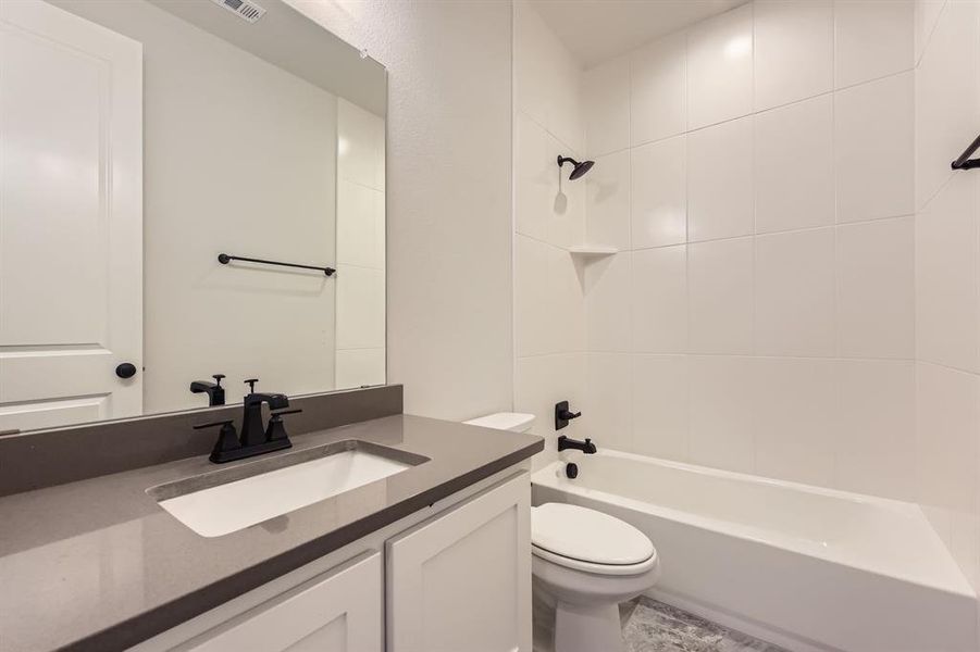 Bathroom featuring toilet, vanity, and  shower combination
