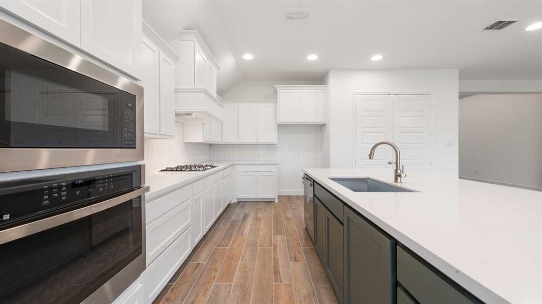 Kitchen with sink, appliances with stainless steel finishes, decorative backsplash, white cabinets, and light wood-type flooring