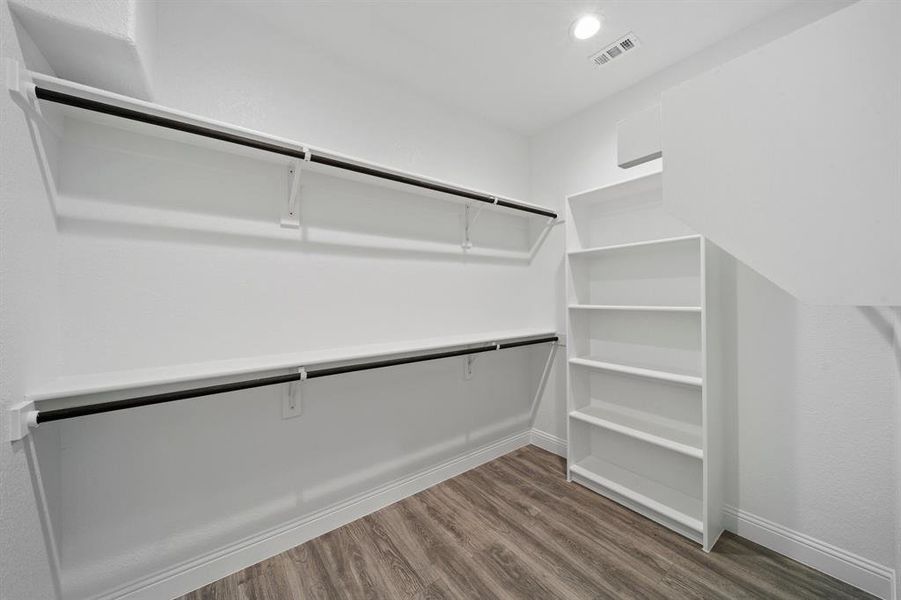 Walk in closet with hardwood / wood-style flooring