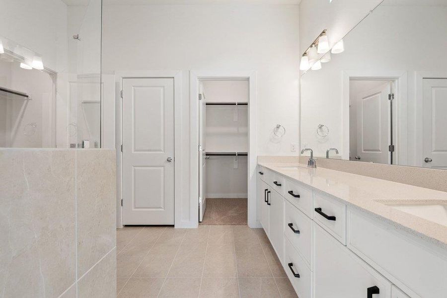 Bathroom featuring double vanity, a walk in shower, light tile patterned floors, and a spacious closet