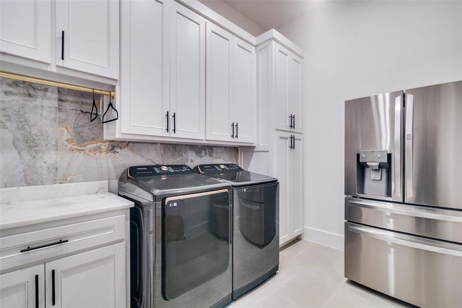 Washroom featuring cabinets, light tile patterned flooring, and washing machine and dryer