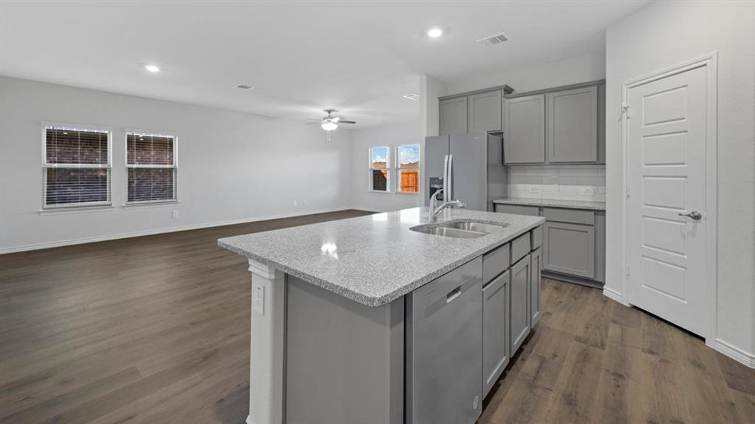 Kitchen with gray cabinets, open floor plan, appliances with stainless steel finishes, dark wood finished floors, and a kitchen island with sink Kitchen with gray cabinets, open floor plan, appliances with stainless steel finishes, dark wood finished floors, and a kitchen island with sink