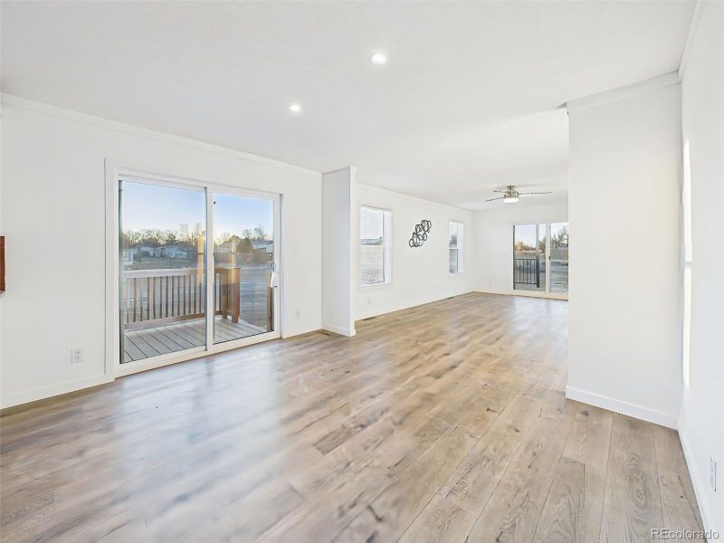 Dining Room This bright, open-concept kitchen and dining space features crisp white cabinetry, stainless steel appliances, and a center island with bar seating. A sliding glass door leads directly to the back deck, perfect for indoor-outdoor dining.