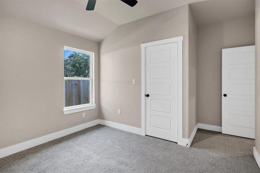 Unfurnished bedroom featuring carpet, lofted ceiling, and a ceiling fan Unfurnished bedroom featuring carpet, lofted ceiling, and a ceiling fan