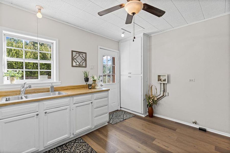 Kitchen featuring dark wood-style flooring, white cabinetry, ceiling fan, ornamental molding, and wooden counters
